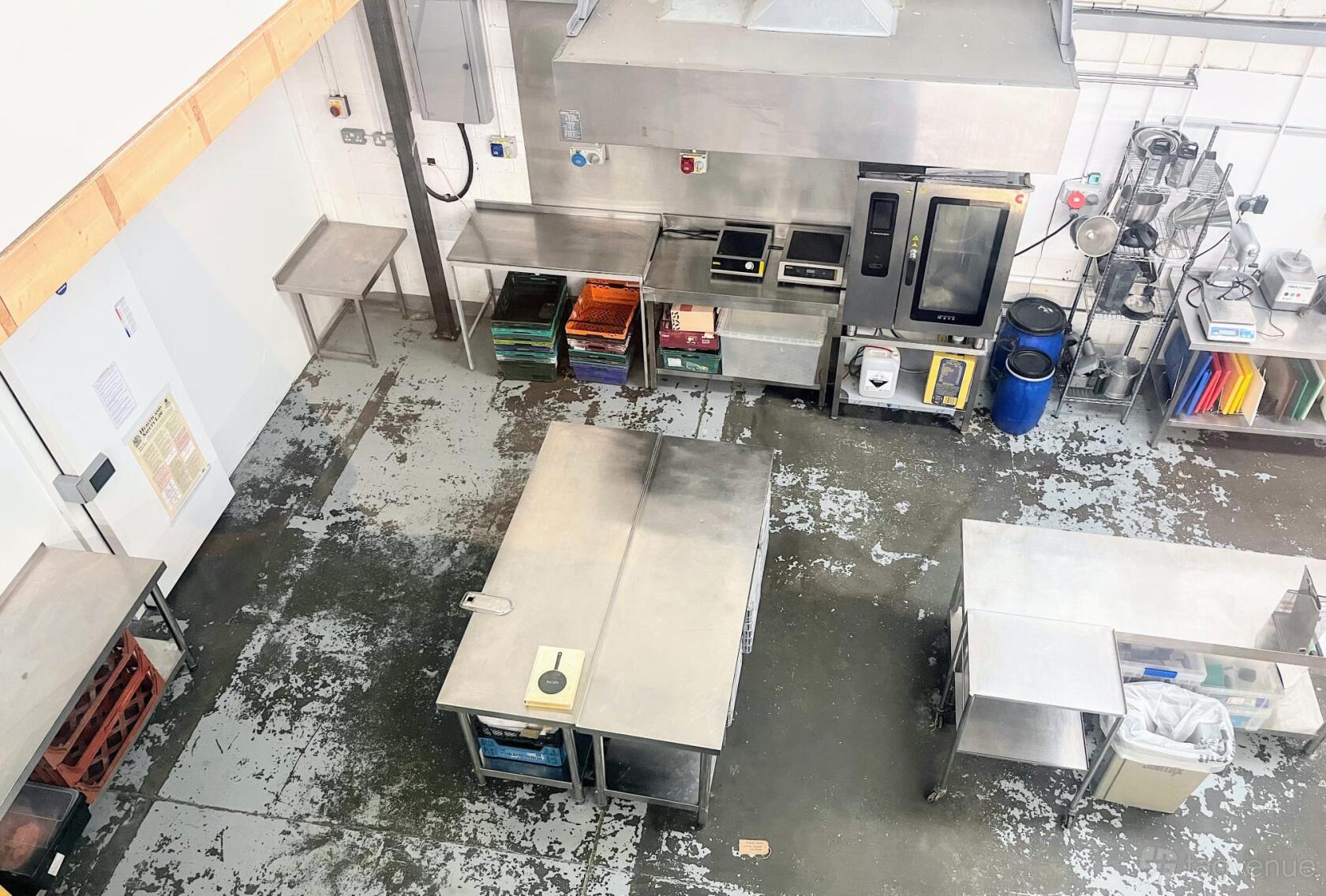 A commercial kitchen with stainless steel work tables, oven, and storage shelves at Canababes Food Co.