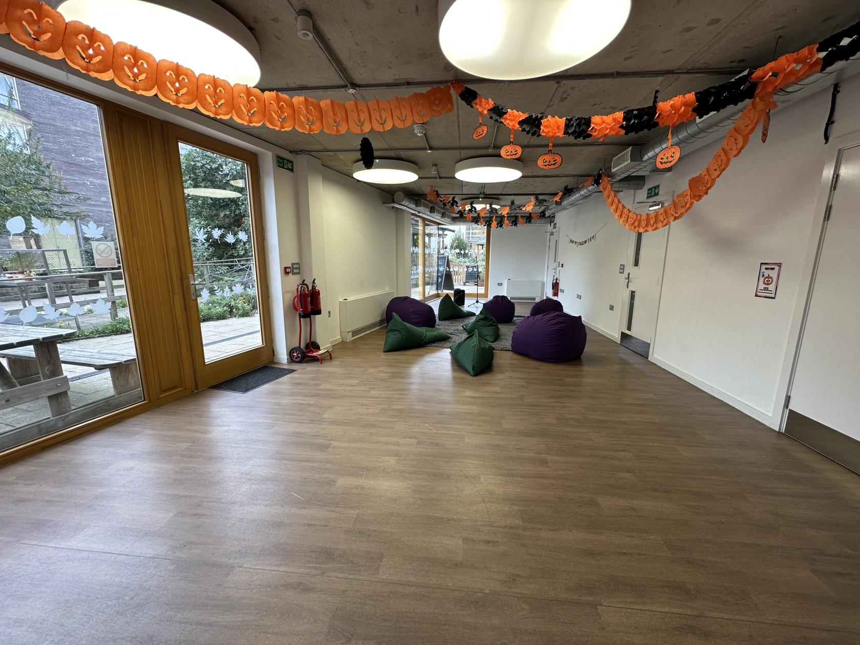 An event venue with floor-to-ceiling windows, bean bags, wood floors, and Halloween decorations at Vauxhall City Farm.