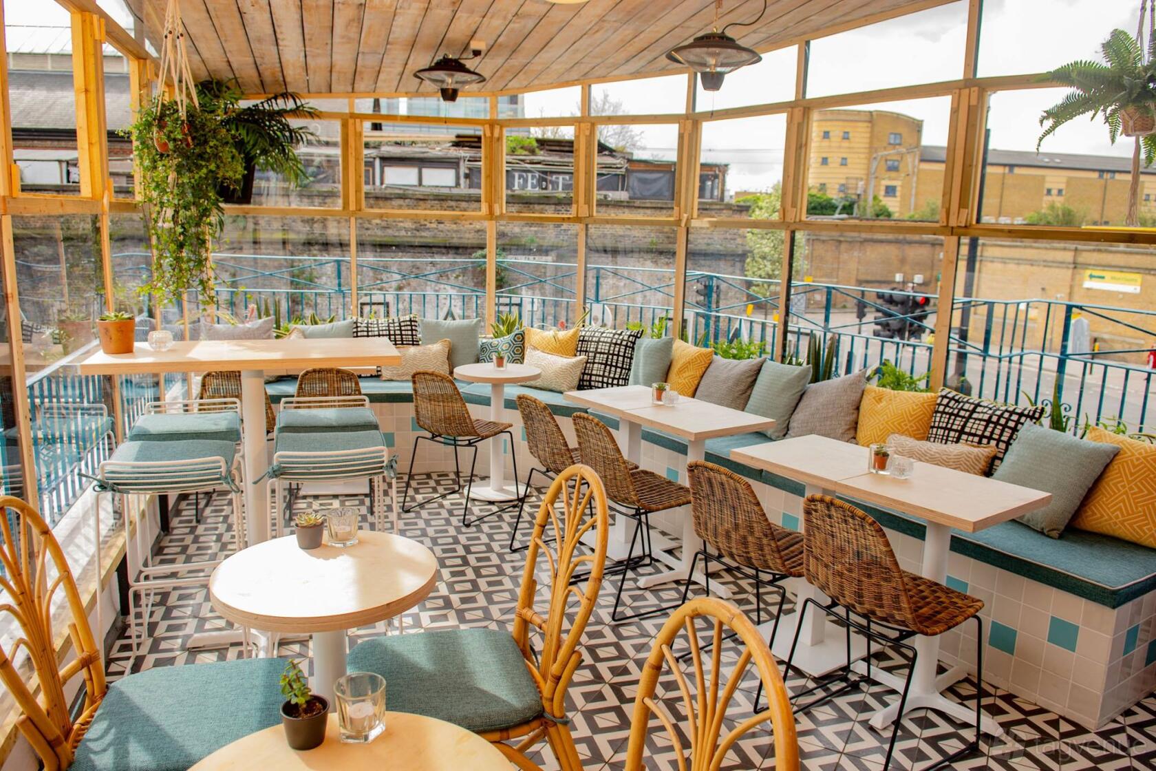 A cocktail bar with tiled floors, cushioned bench seating, and large windows at Studio48 Bar & Kitchen.