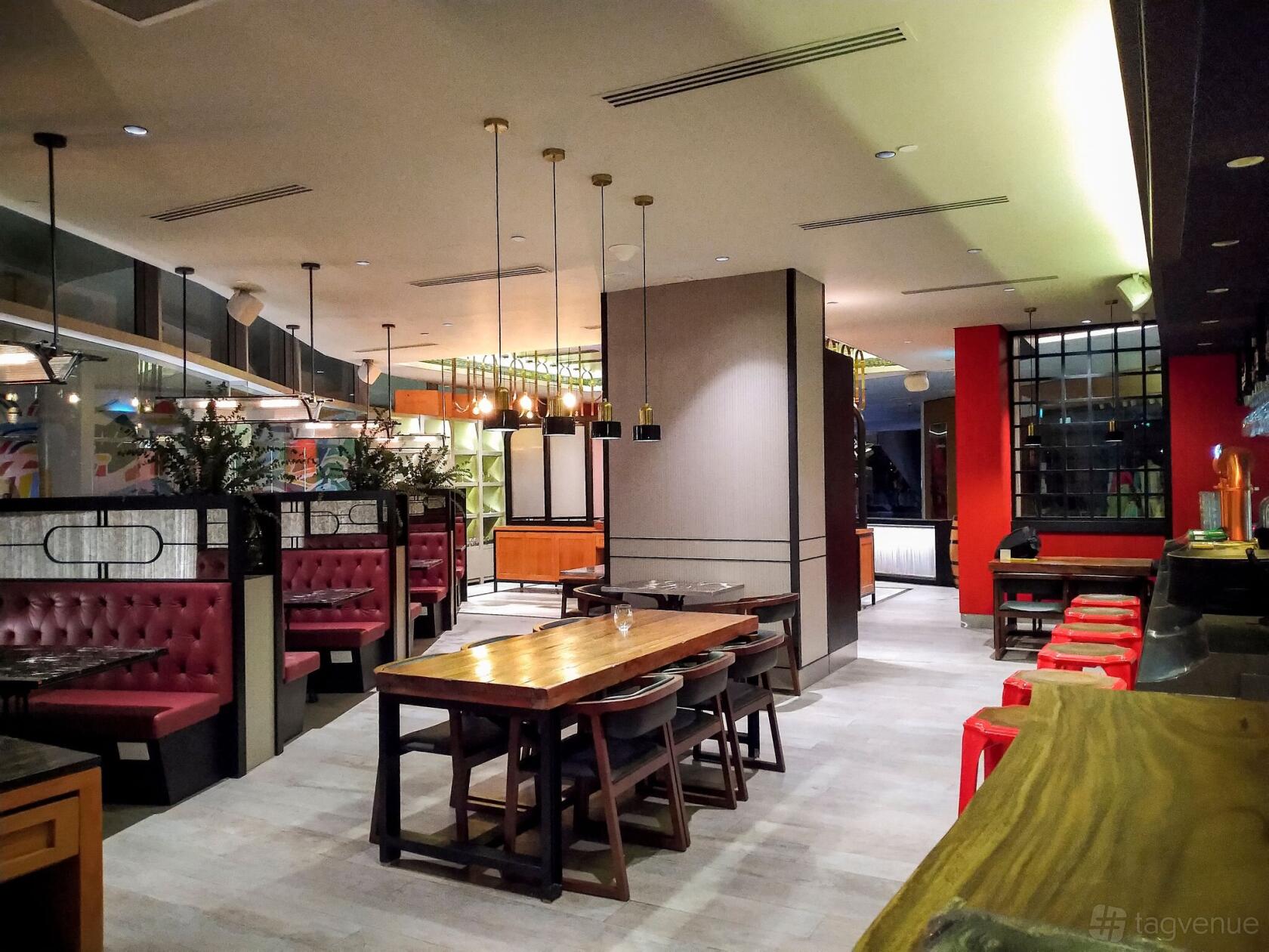 An event space in a restaurant with wood tables, red banquette seating, pendant lighting, and a bar at Barossa Steak & Grill.