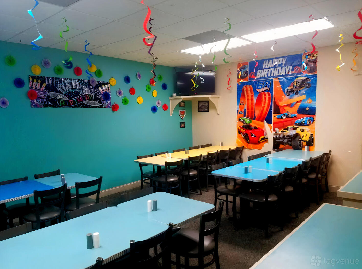 A dining room with long turquoise tables, black chairs, and birthday decorations at Mr. Gatti's Kingwood.