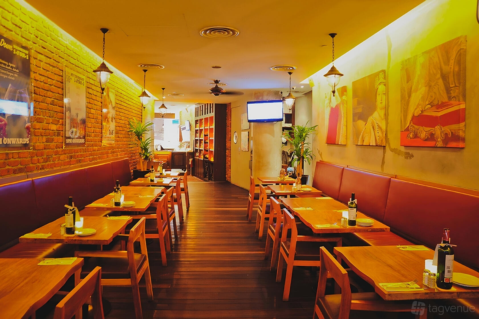 A restaurant with exposed brick walls, wooden tables, red cushioned seating, and warm lighting at The Queen and Mangosteen.