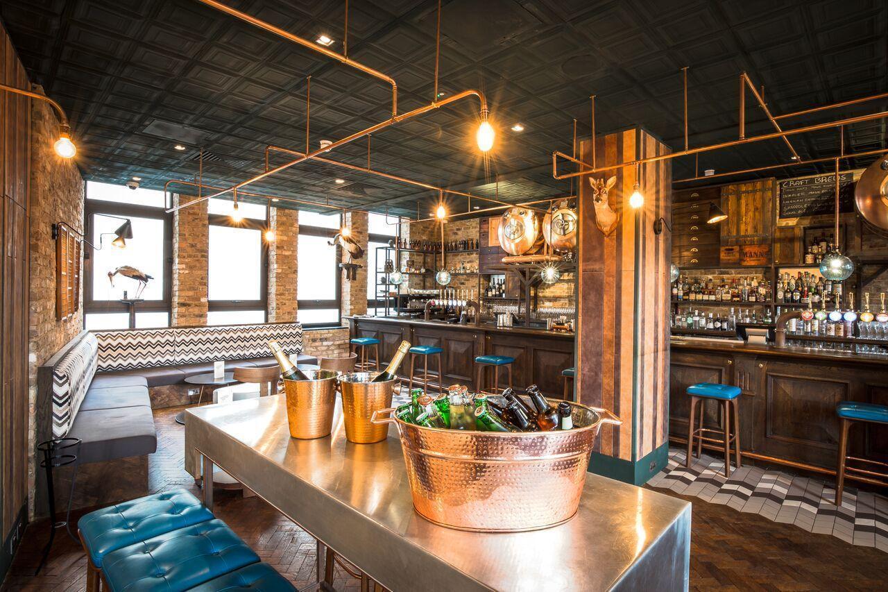 An event space in a pub with copper accents, a central table with ice buckets, and eclectic bar seating at Burdock.