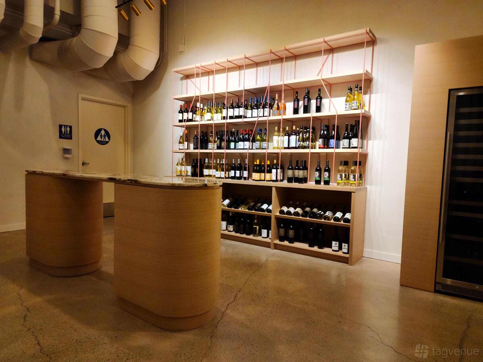 An event space in a bar with a marble-topped counter and a wall display of wine bottles at CoCo Noir Wine Shop & Bar.