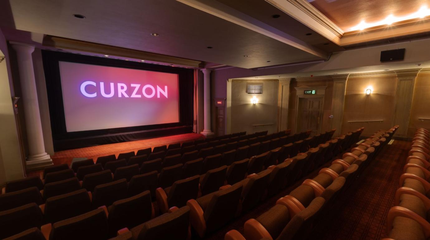 A screening room with tiered seating, a large projection screen, and soft lighting at Curzon Richmond.