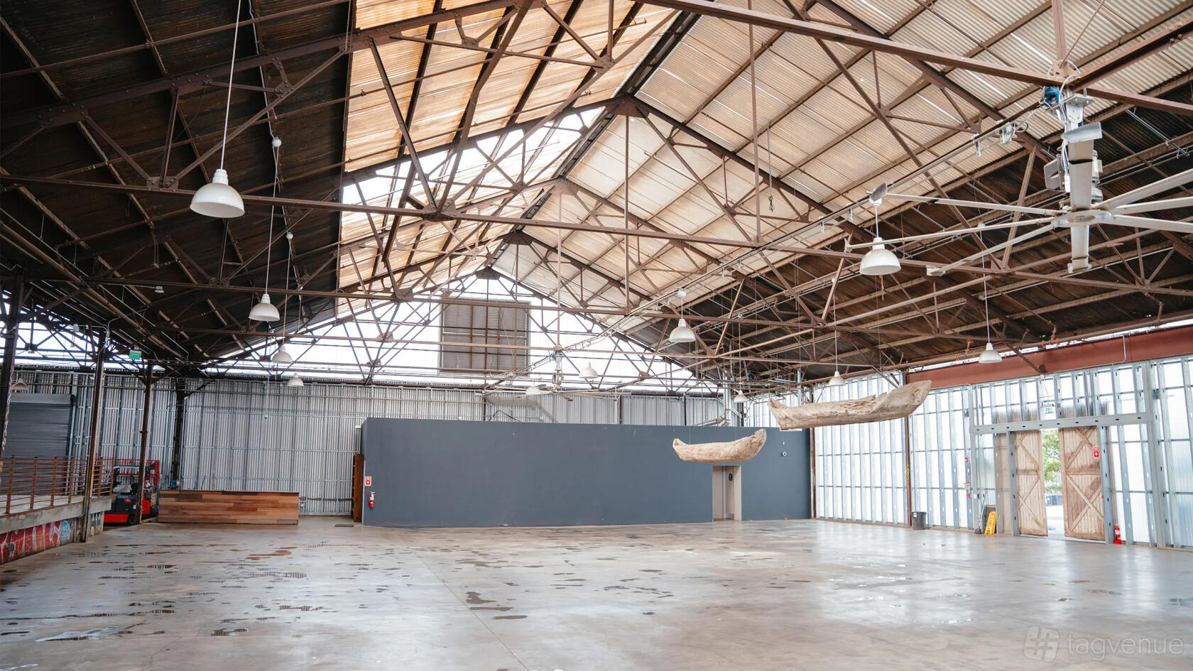 An event venue with high exposed beam ceilings, large industrial windows, and concrete floors at Rolling Greens On Mateo.