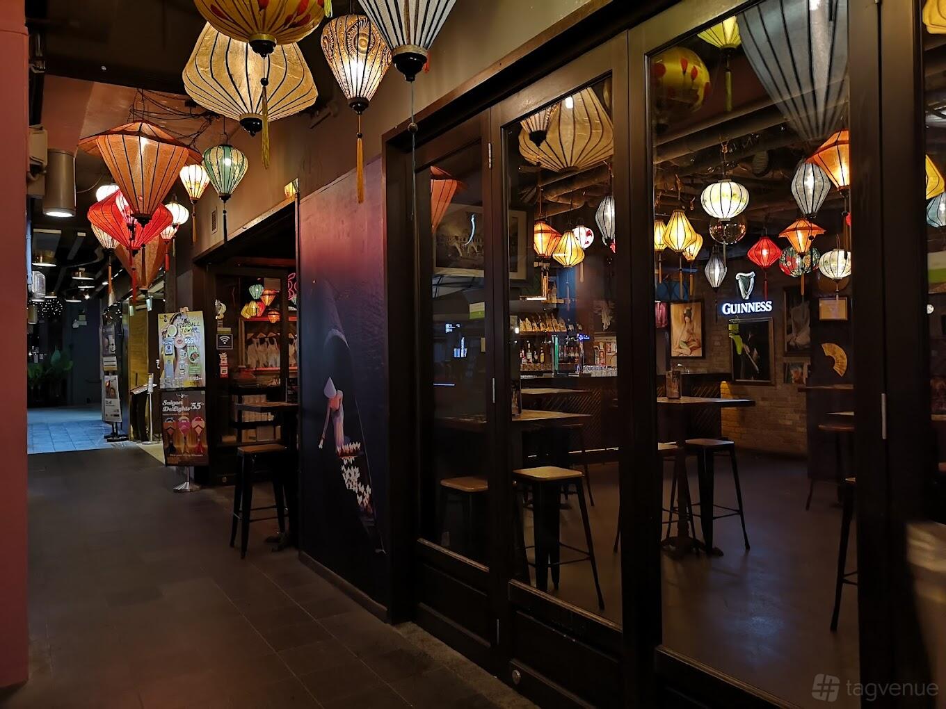 An event space in a restaurant with colorful hanging lanterns and wooden high tables at Little Saigon.