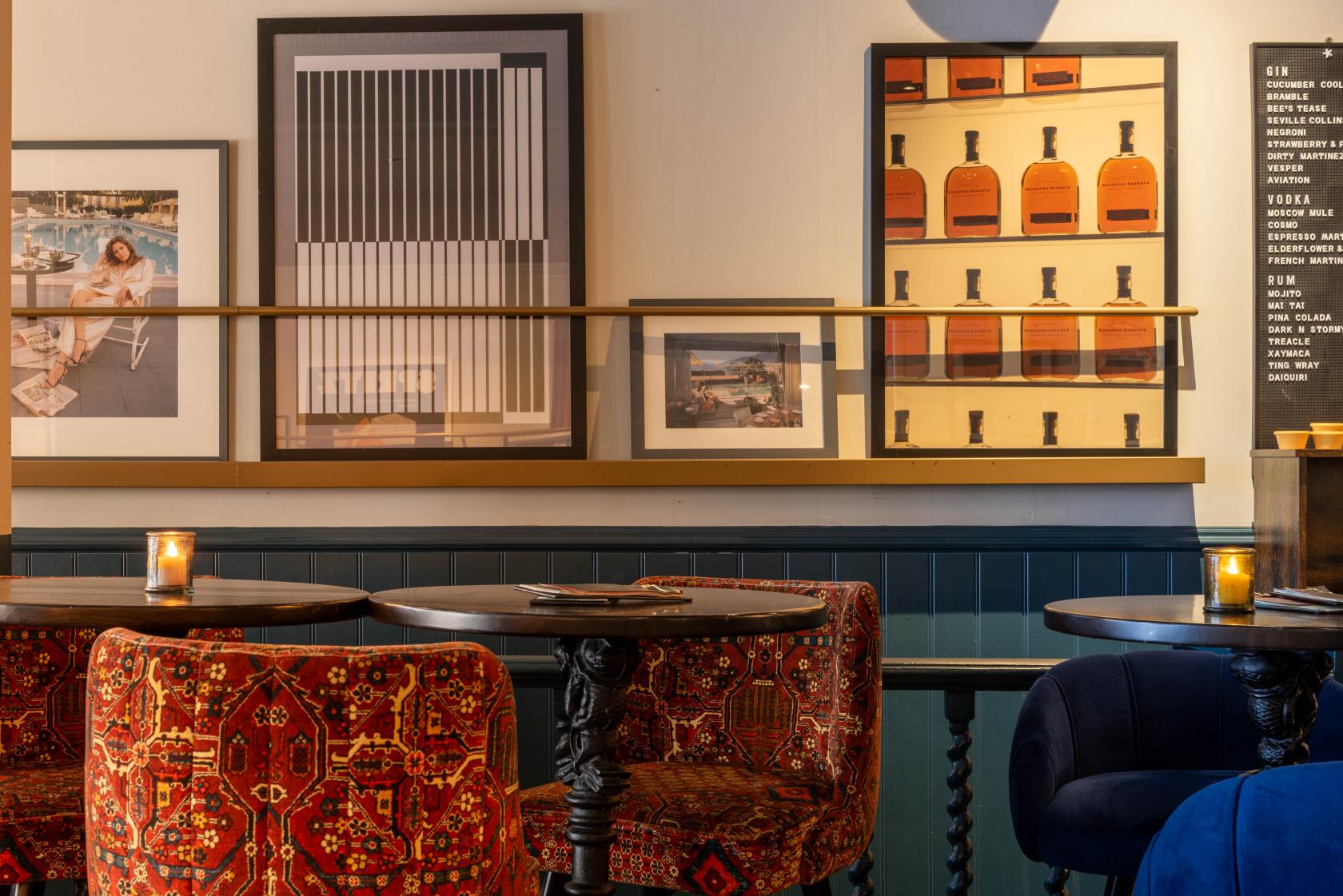 An event space with patterned red chairs, round dark wood tables, and framed artwork at LOCKES Bar Covent Garden.