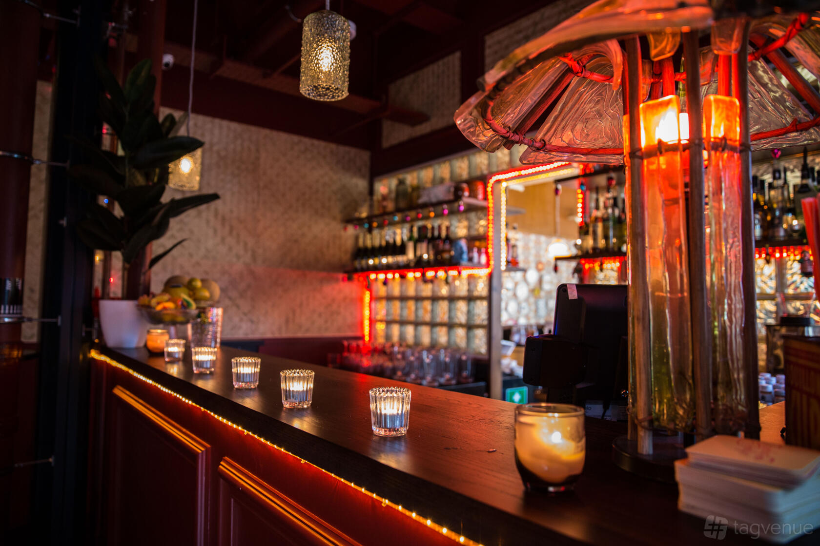 A restaurant bar with glowing candle votives, glass block wall, and shelves of liquor at The Breakfast Club Oxford.