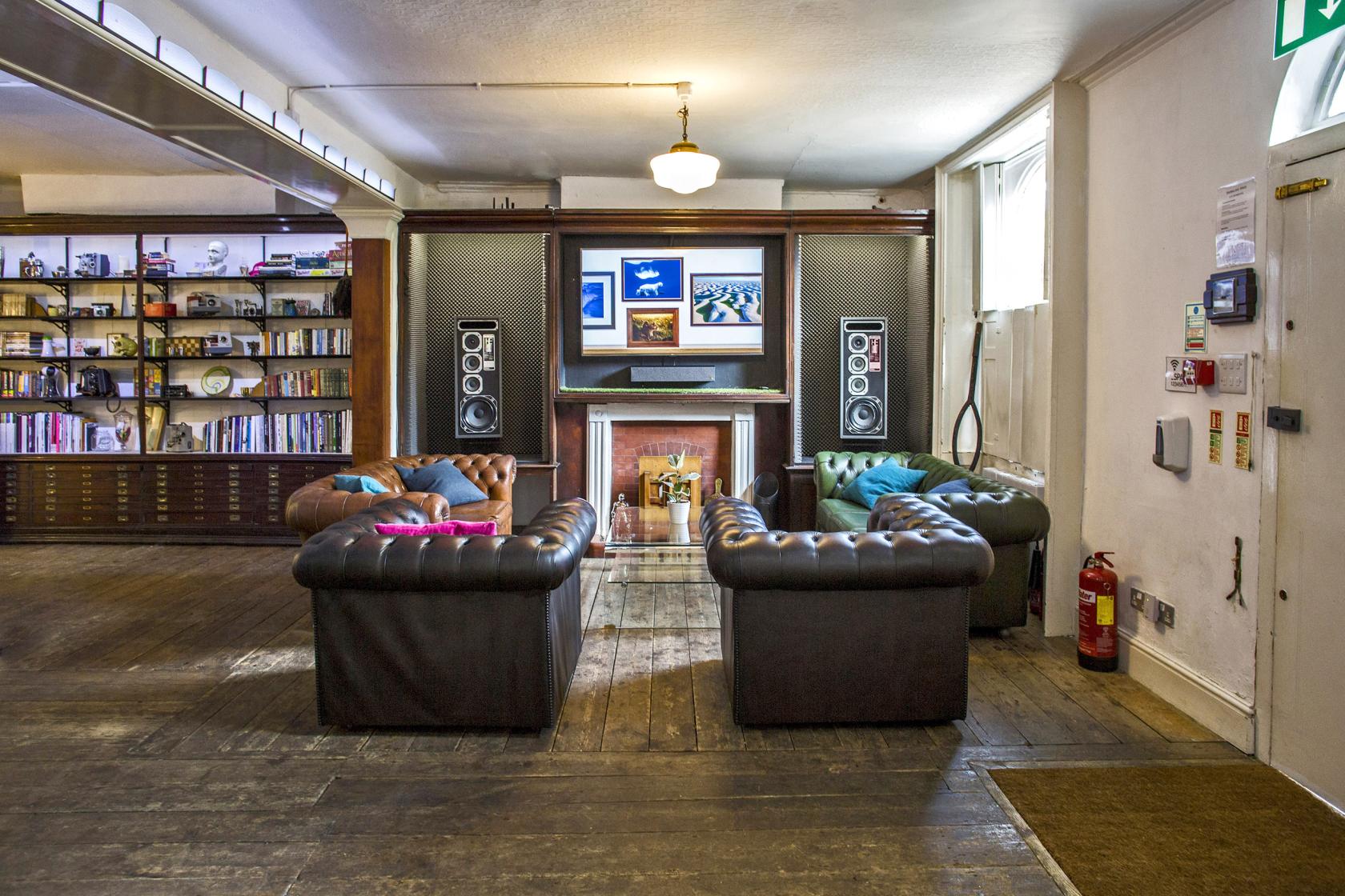 An event space with leather sofas, wooden floors, and a wall of bookshelves at Anomalous Space.