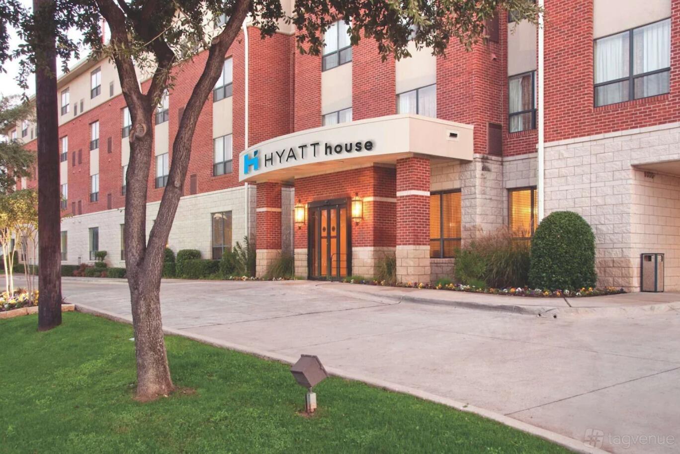 A hotel with a red brick exterior, large windows, and a covered entrance at Hyatt House Dallas/Uptown.