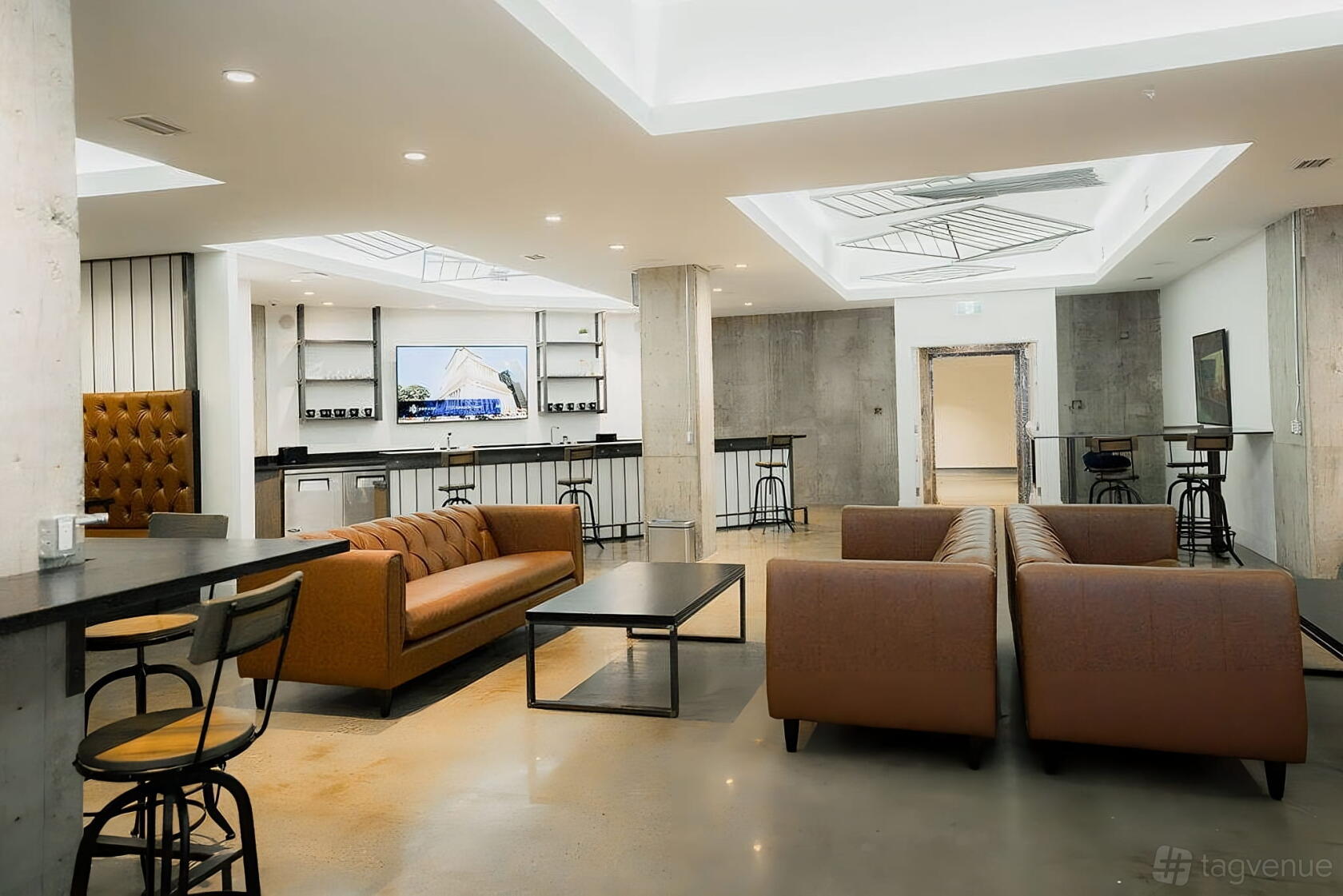 An event space with leather sofas, polished concrete floors, and a built-in bar at iQ Offices - 250 University Avenue.