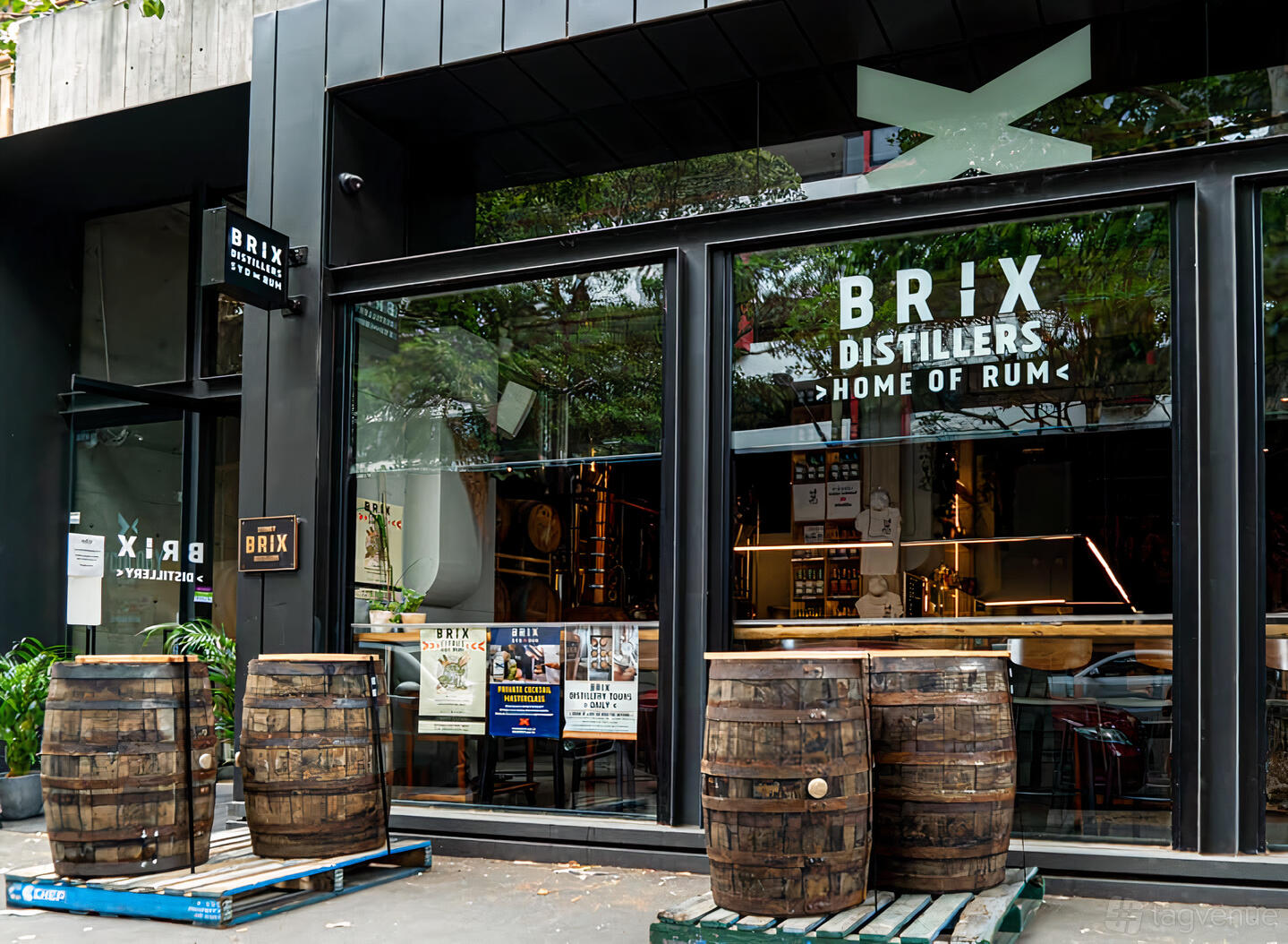 A pub with floor-to-ceiling windows, wooden barrels outside, and prominent Brix Distillers signage at Brix Distillery.