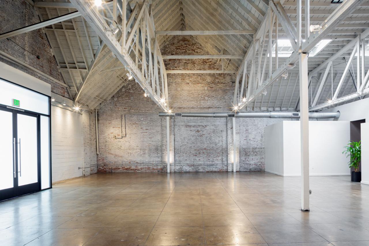 A warehouse with exposed brick walls, high beamed ceilings, and polished concrete floors at Honeypot LA.
