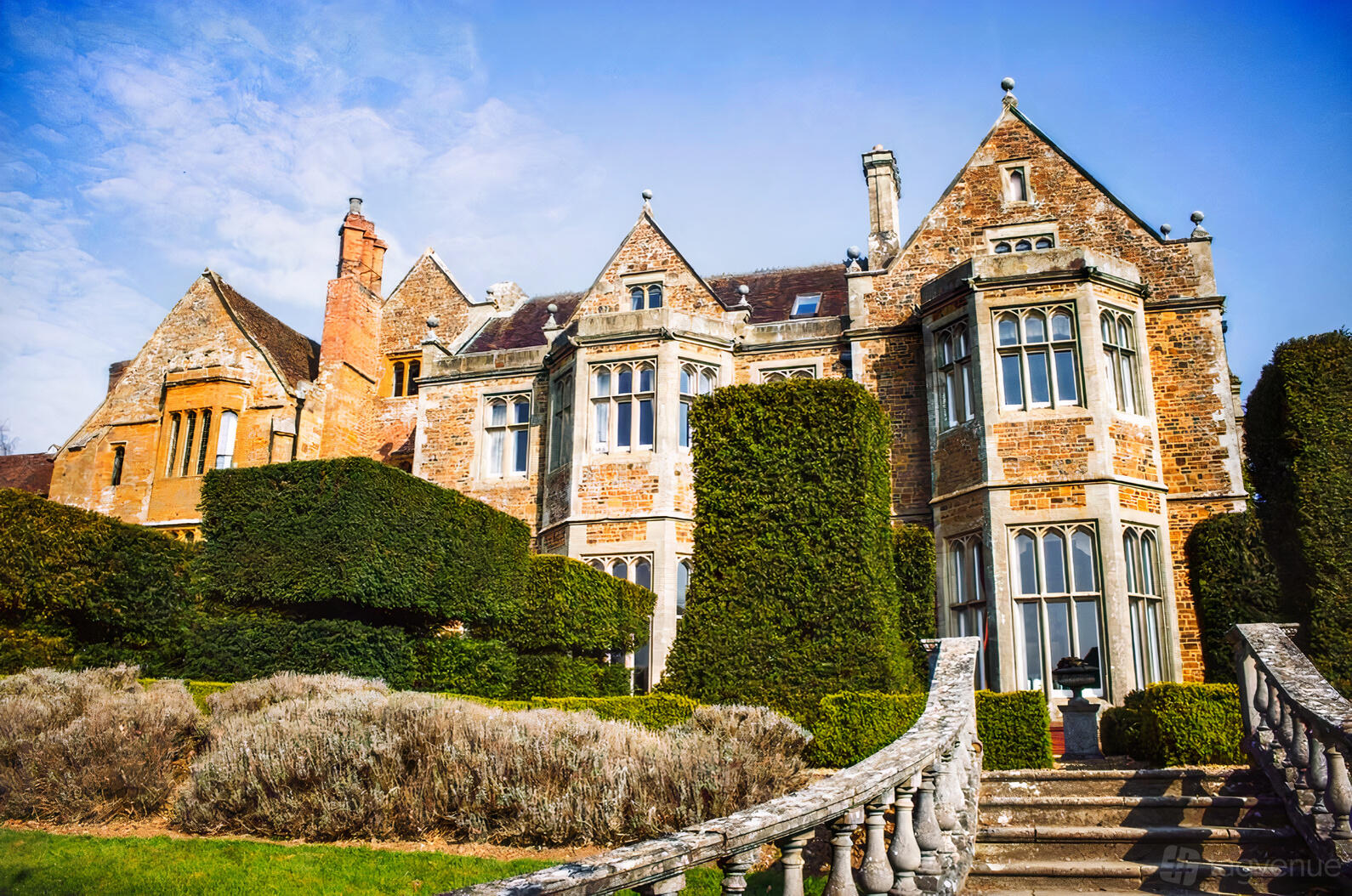 A historic hotel with stone facade, tall windows, and manicured hedges at Fawsley Hall Hotel.