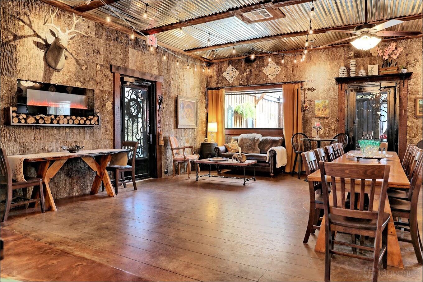 An event venue with wood-paneled walls, string lights, rustic decor, and a long dining table at Azle Deer Cove.