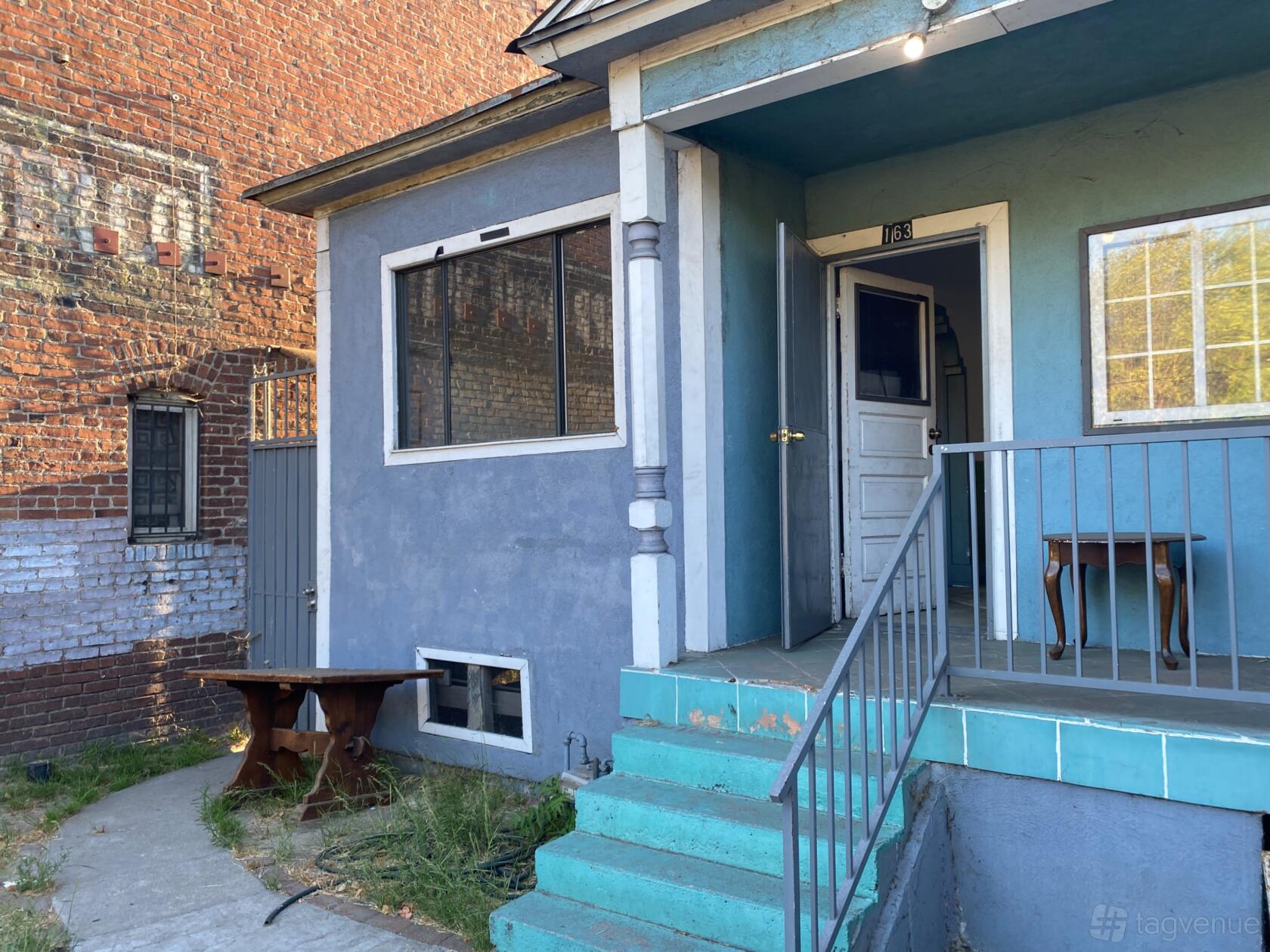 An apartment with turquoise steps, a small front porch, and exposed brick walls at Downtown Apartments.