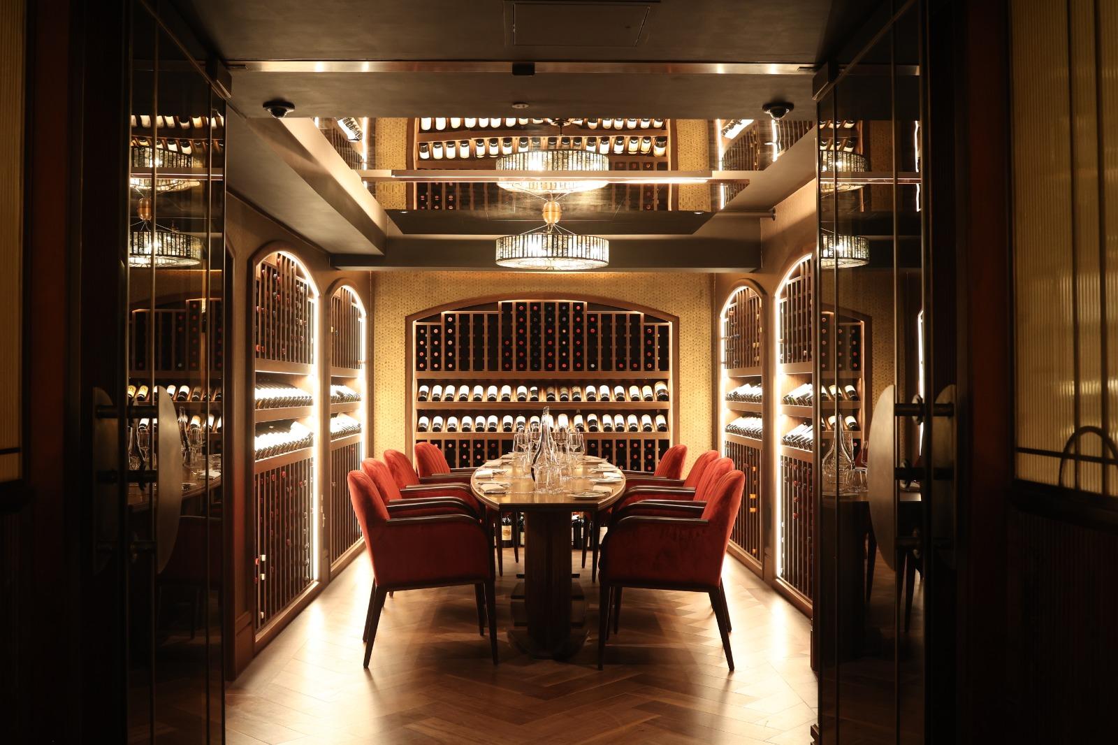A private dining room with glass wine cabinets, a polished wooden table, and red upholstered chairs at Savoy Grill.