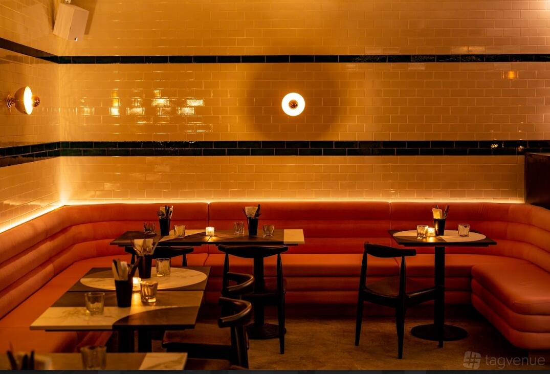 An event space in a nightclub with orange leather banquette seating, tiled walls, and candles on tables at Le Bab Covent Garden.