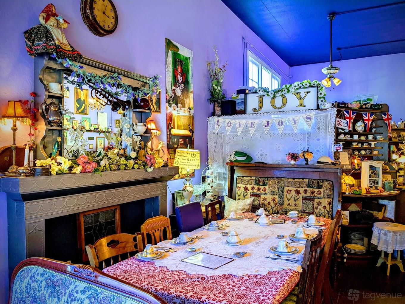 A cafe with floral decor, vintage furniture, and a table set for tea service at Lovejoy's Tea Room.