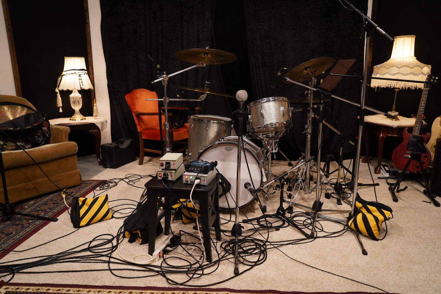 A music studio with a drum kit, vintage lamps, and scattered audio equipment at Shoreline Studios.