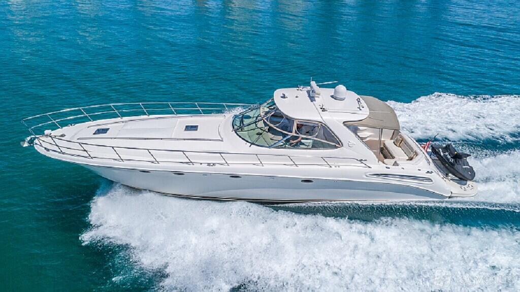 A white yacht cruising on blue water with a spacious deck and open seating area at Pearl Yacht Charters.
