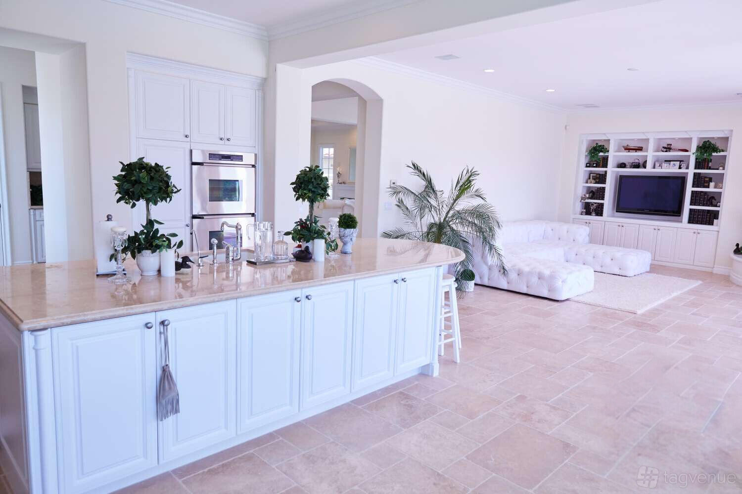 A country house with a spacious open-plan kitchen, white cabinetry, and a living area with tufted sofas at LUXURIOUS FRENCH COUNTRY ESTATE.