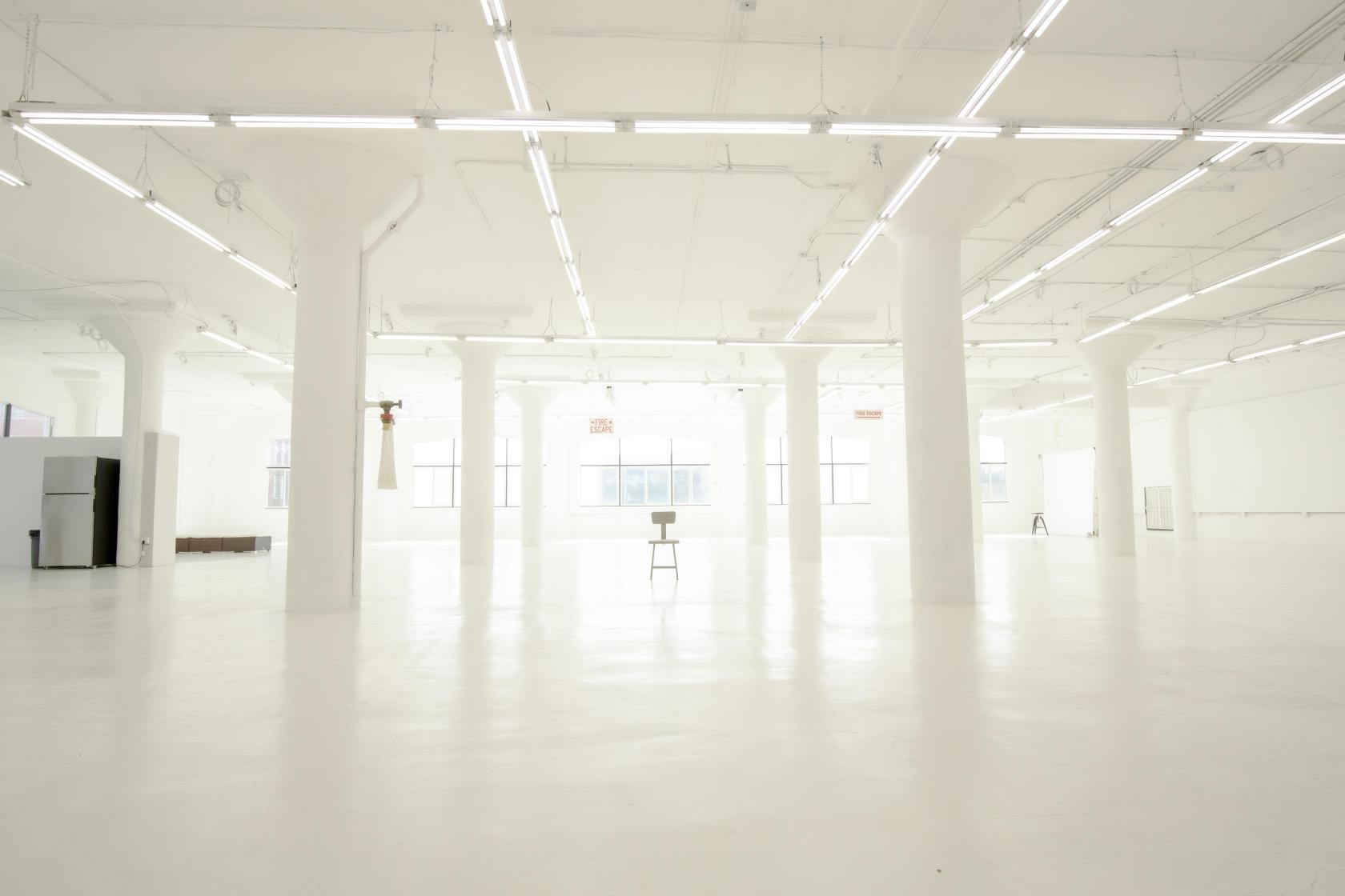 An open event venue with white floors, tall columns, and large industrial windows at Elysium DTLA.