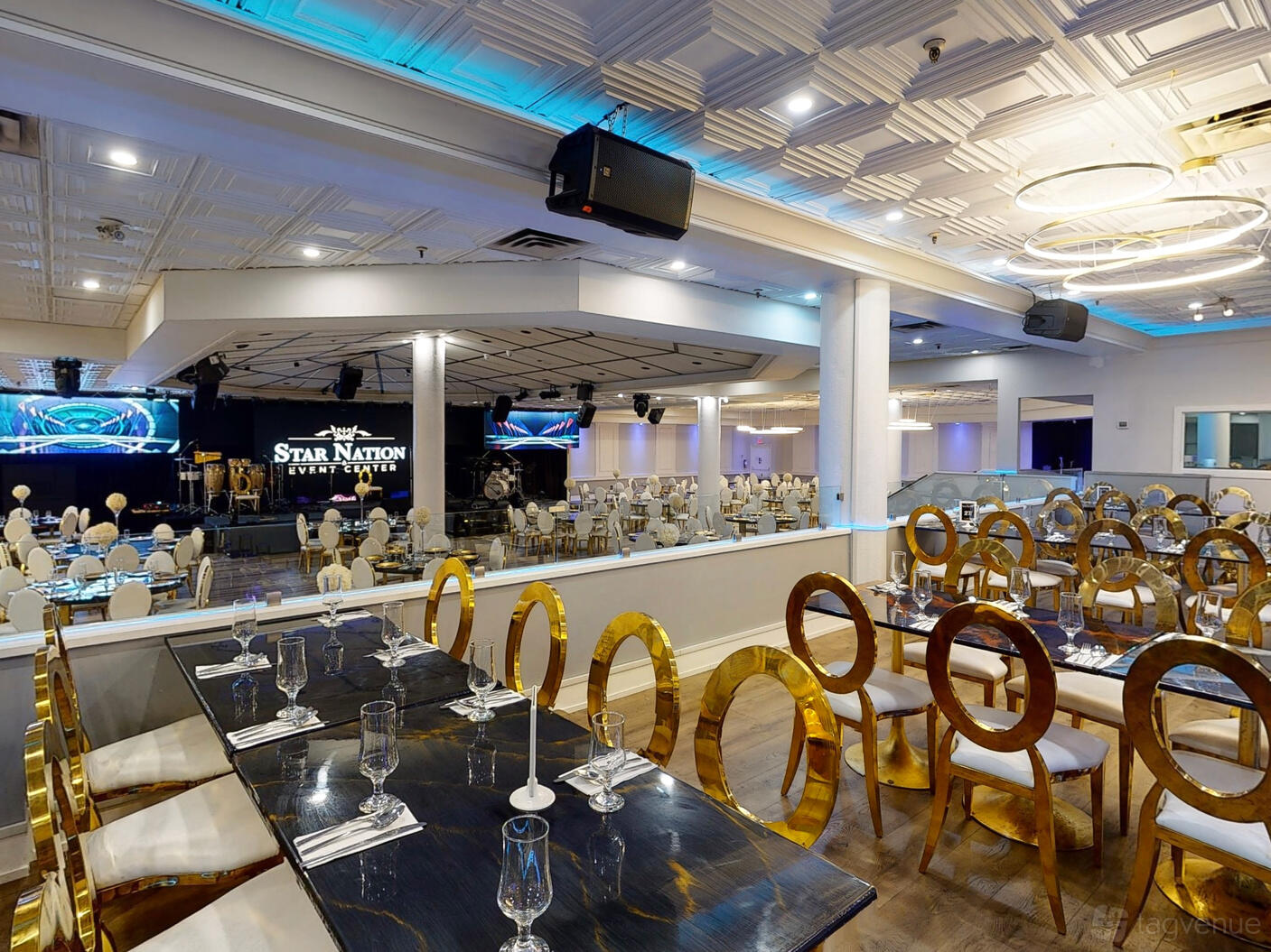 An event space with gold-backed chairs, black marble tables, and stage views at Star Nation.