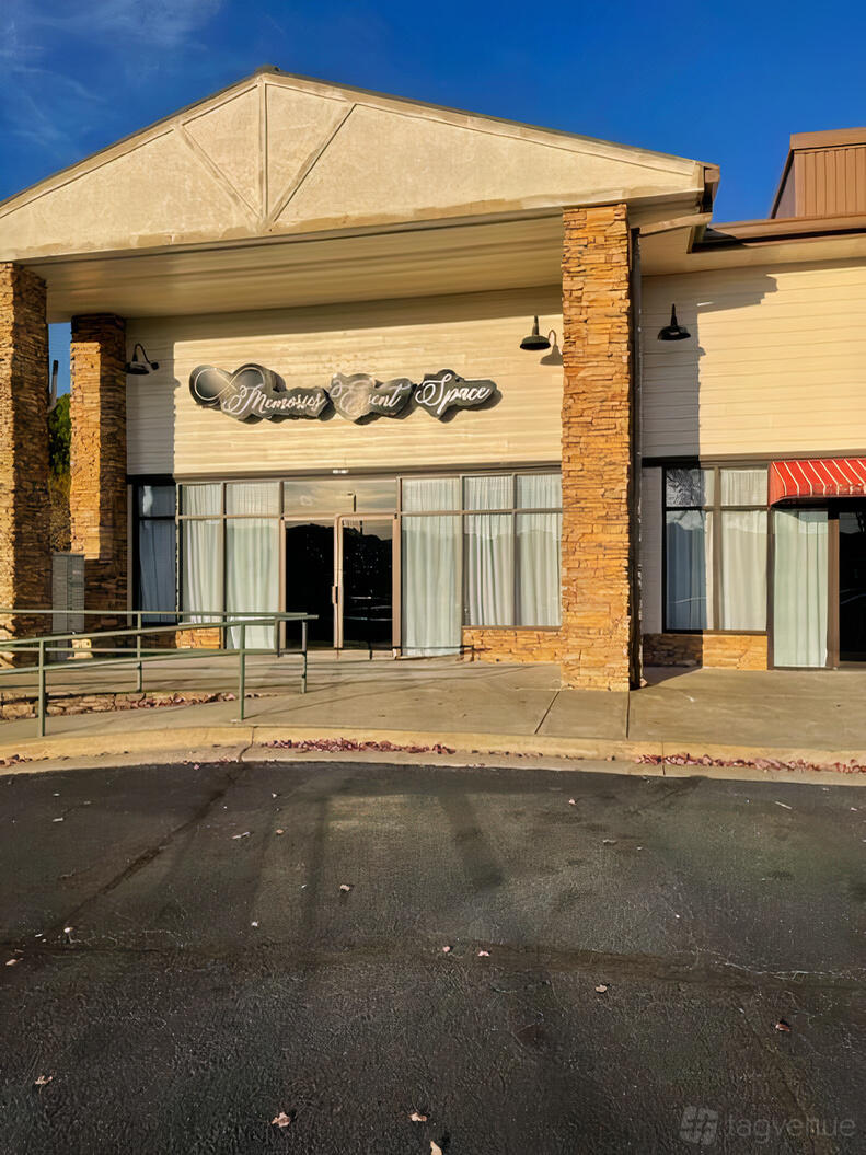 An event venue entrance with large glass doors, floor-to-ceiling windows, and stone columns at Memories Event Space.