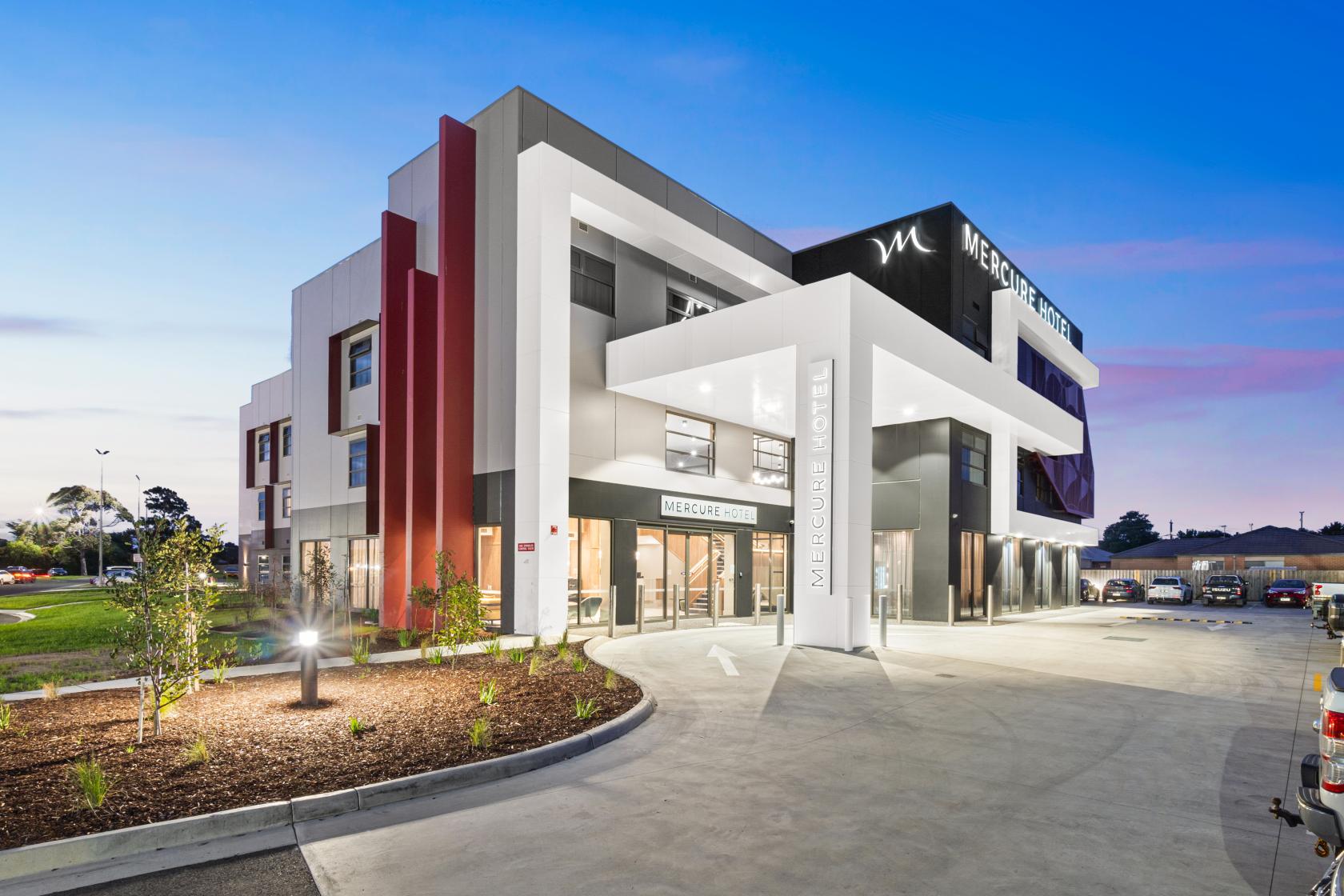 A hotel with geometric architectural features, large entry canopy, and illuminated signage at Mercure Pakenham.