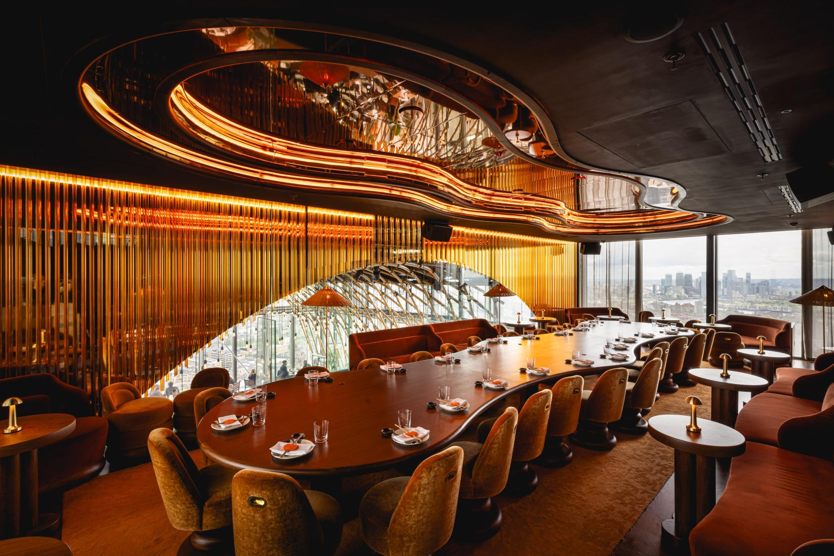 A private dining room with a long oval table, plush velvet chairs, and a mirrored ceiling at SUSHISAMBA.