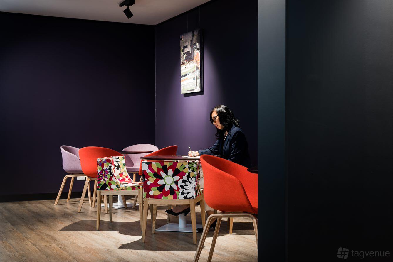 A coworking space with colorful chairs, wood flooring, and dark purple walls at Cliftons Canberra – Moore St.