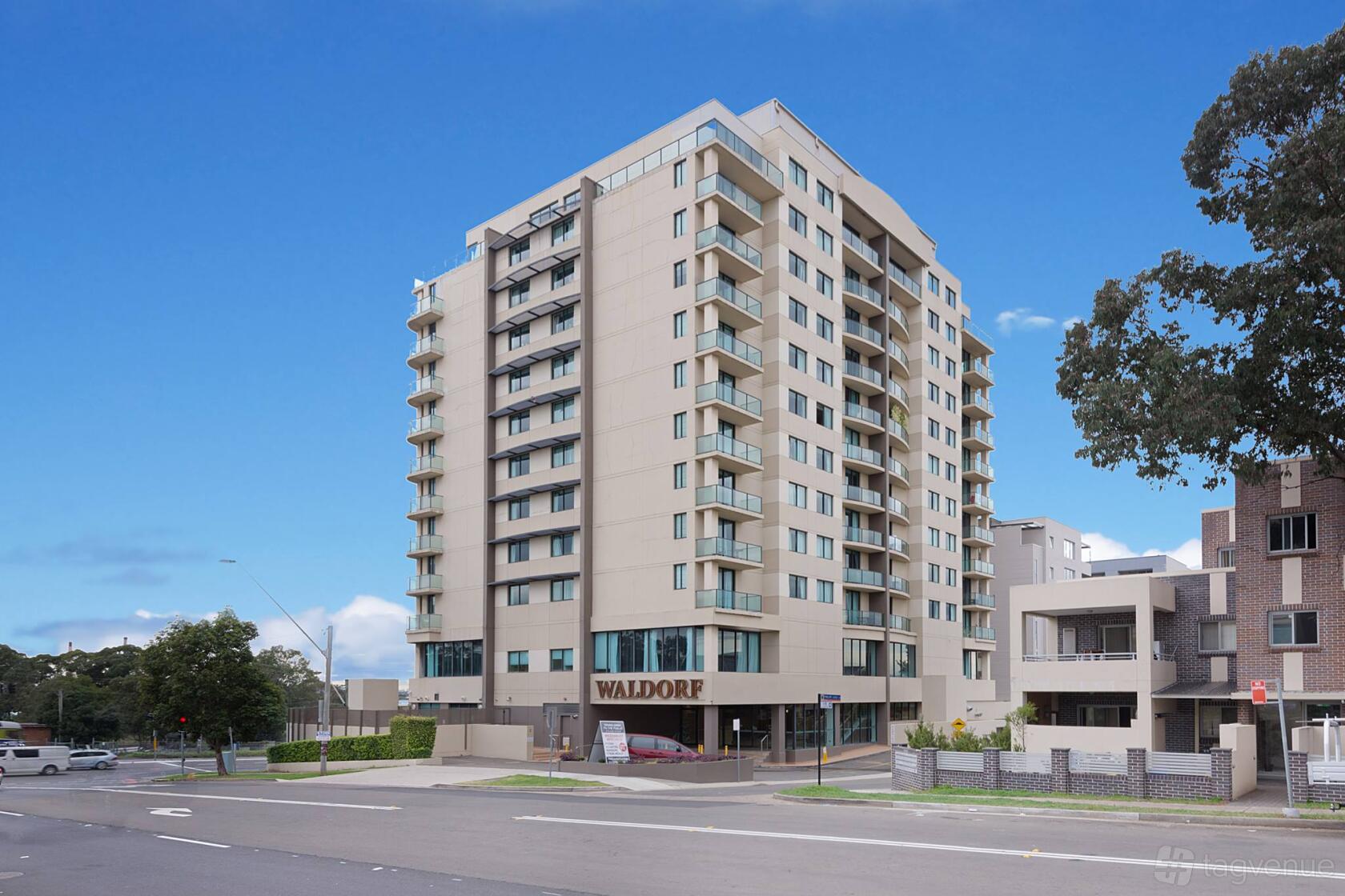 A hotel with a multi-story beige facade, balconies, and street-facing entrance at Nesuto Parramatta Apartment Hotel.
