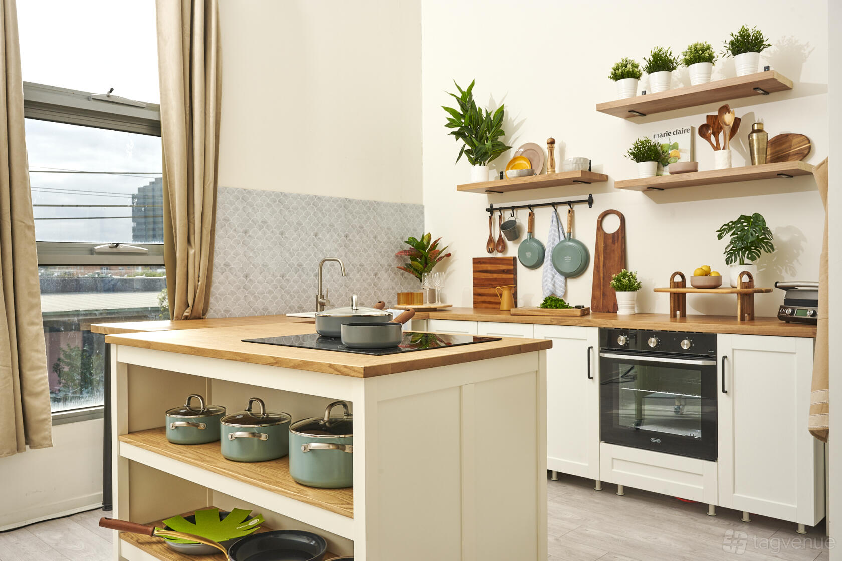 A photo studio with a kitchen set, wooden countertops, open shelving, and potted plants at Food Photography and Media Studio.