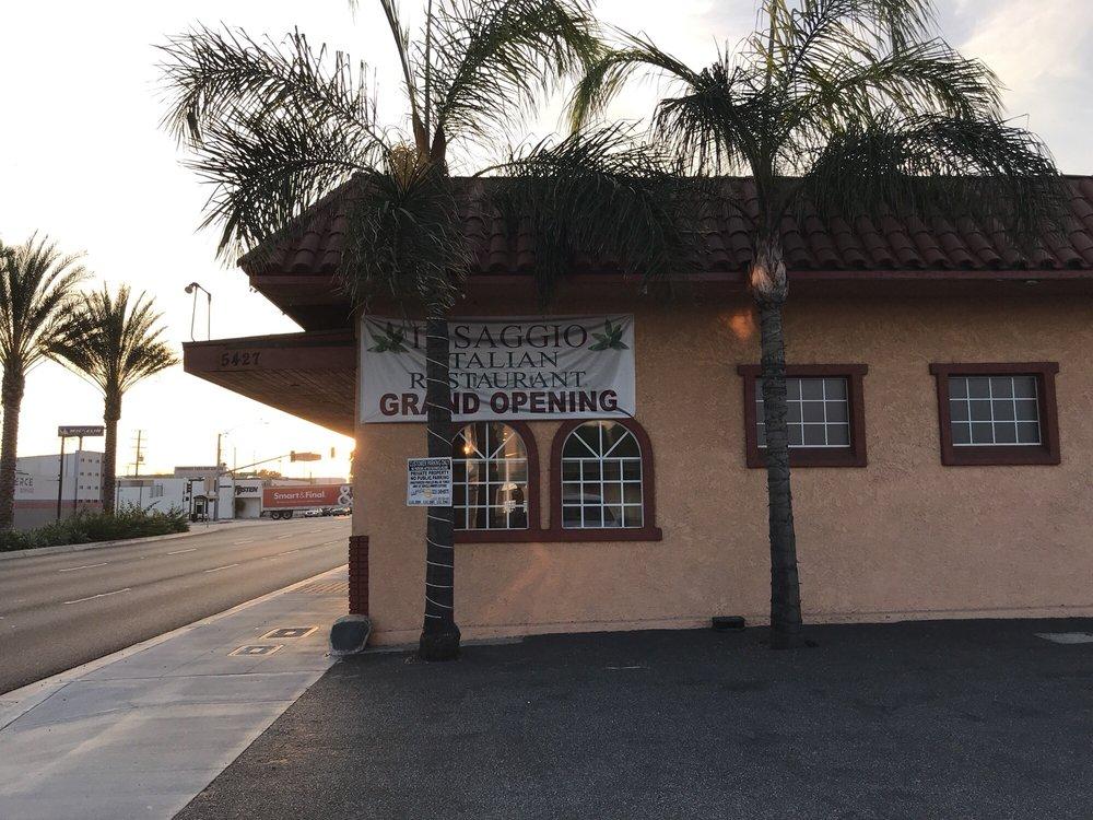 A restaurant with stucco exterior walls, red tile roof, arched windows, and palm trees at Il Saggio Italian Restaurant.
