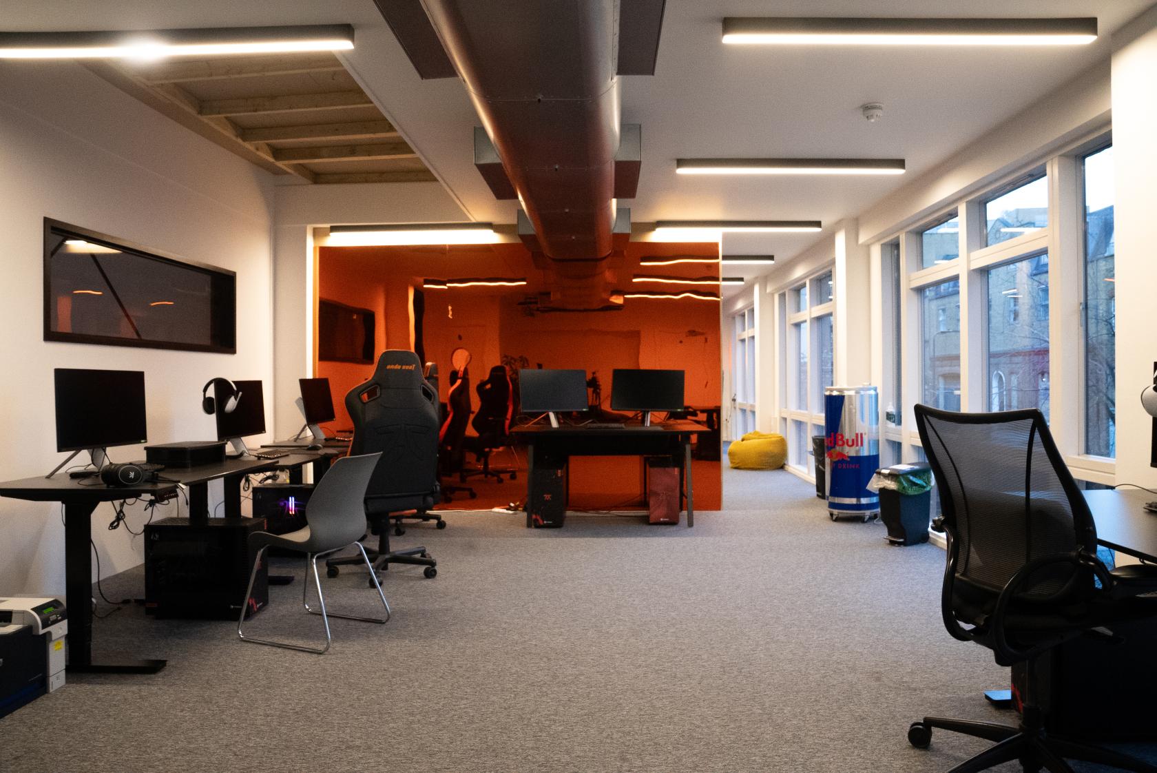 A coworking space with ergonomic chairs, computer desks, and large windows at 1 Kingsland Passage.