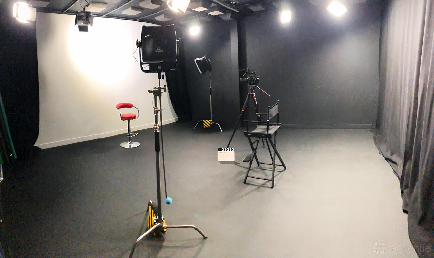 A photo and film studio with video cameras, stage lighting, and a red stool at Up Next Studios.