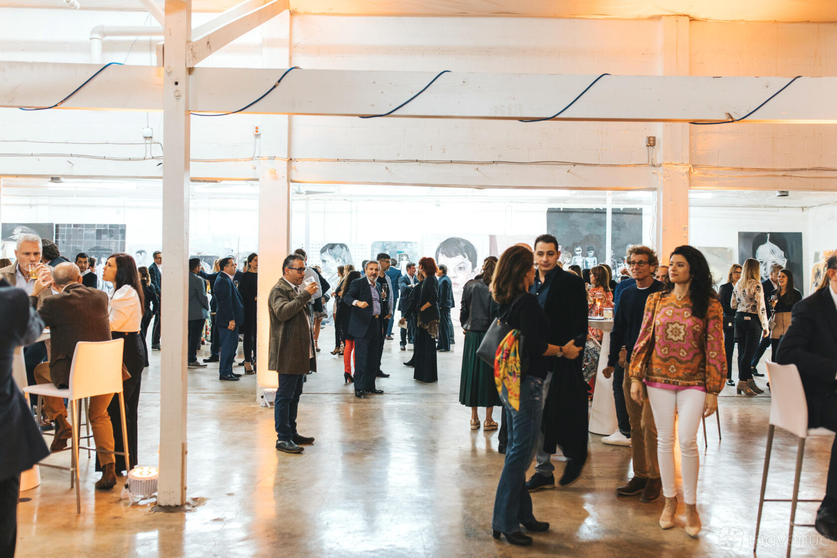 A gallery with polished concrete floors, white pillars, and large black-and-white artwork at MAMAN Fine Art Gallery.