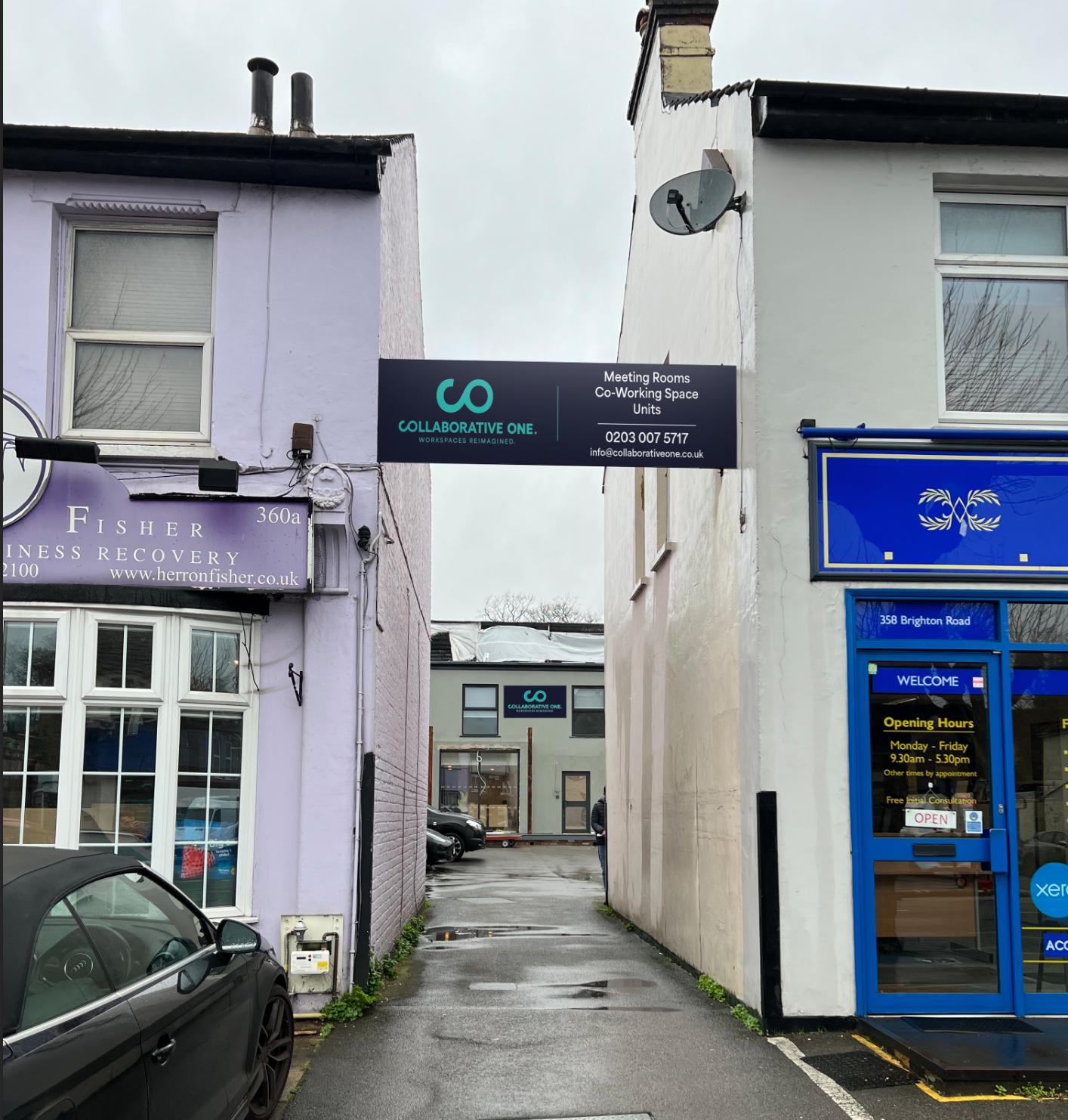 An exterior entrance to a meeting centre with signage for Collaborative One - Flexible Spaces between two buildings.