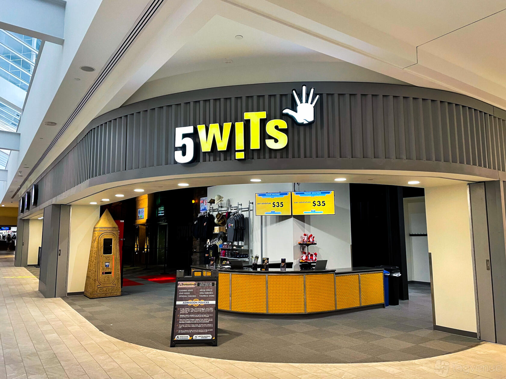A versatile event space with a bold yellow sign, merchandise counter, and interactive display at 5 Wits - Arlington.
