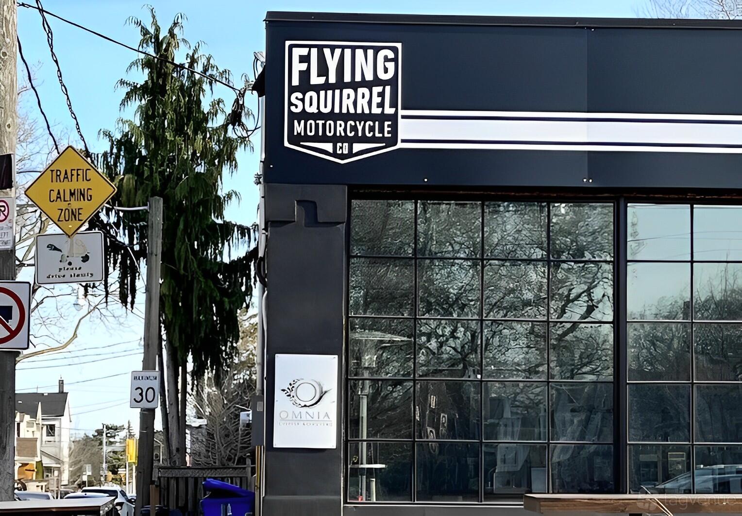 A café with floor-to-ceiling glass windows and bold signage at Flying Squirrel Motorcycle Co.