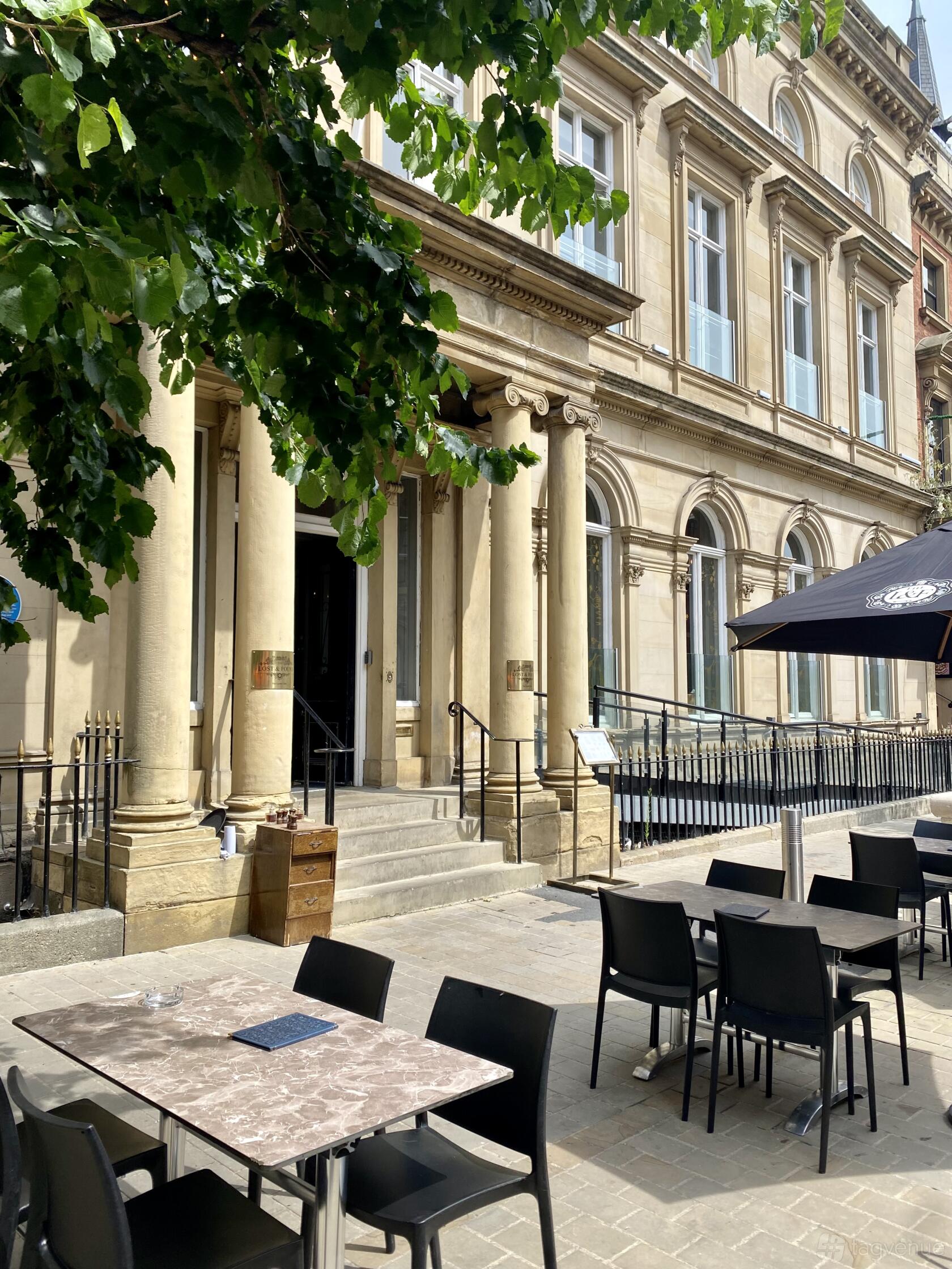 A versatile event space with grand stone columns, arched windows, and outdoor seating at The Lost and Found Leeds Club.