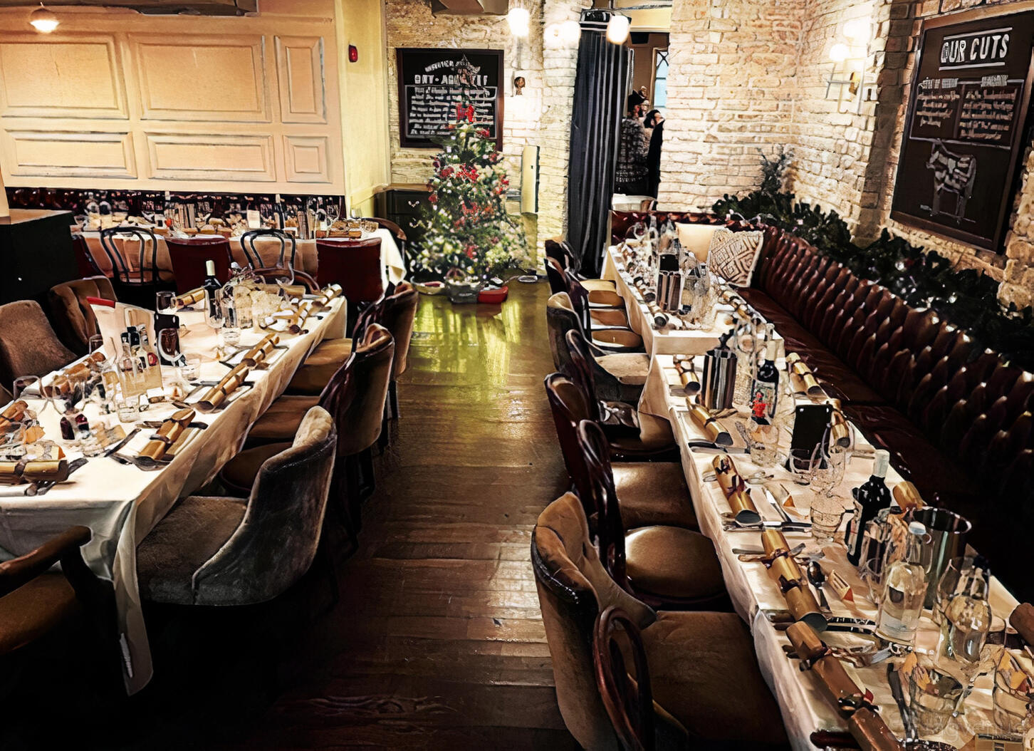 A bar restaurant with long banquet tables, leather chairs, holiday decorations, and exposed brick walls at Balls Brothers Minster Court.
