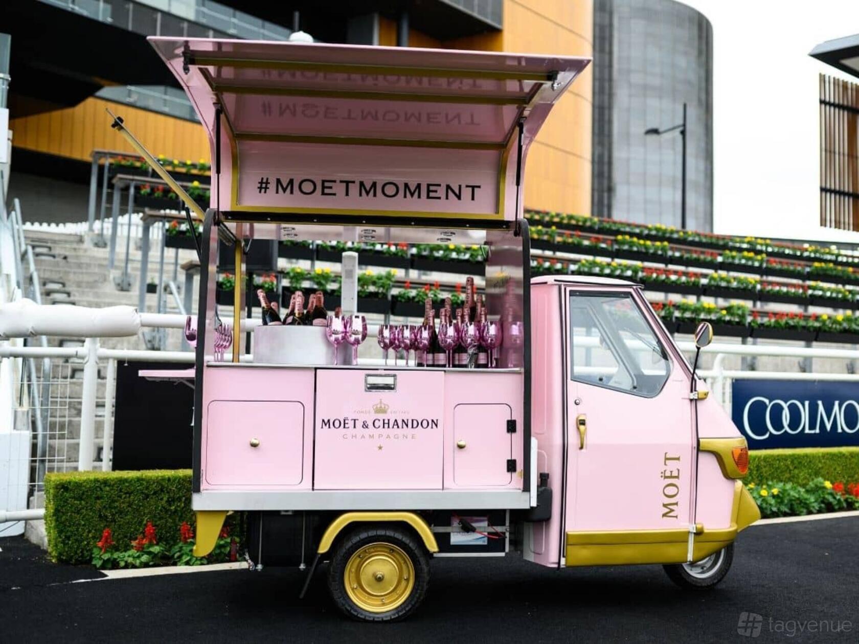 A pink Moët & Chandon champagne cart with glasses and bottles near tiered seating at Australian Turf Club @ Royal Randwick.
