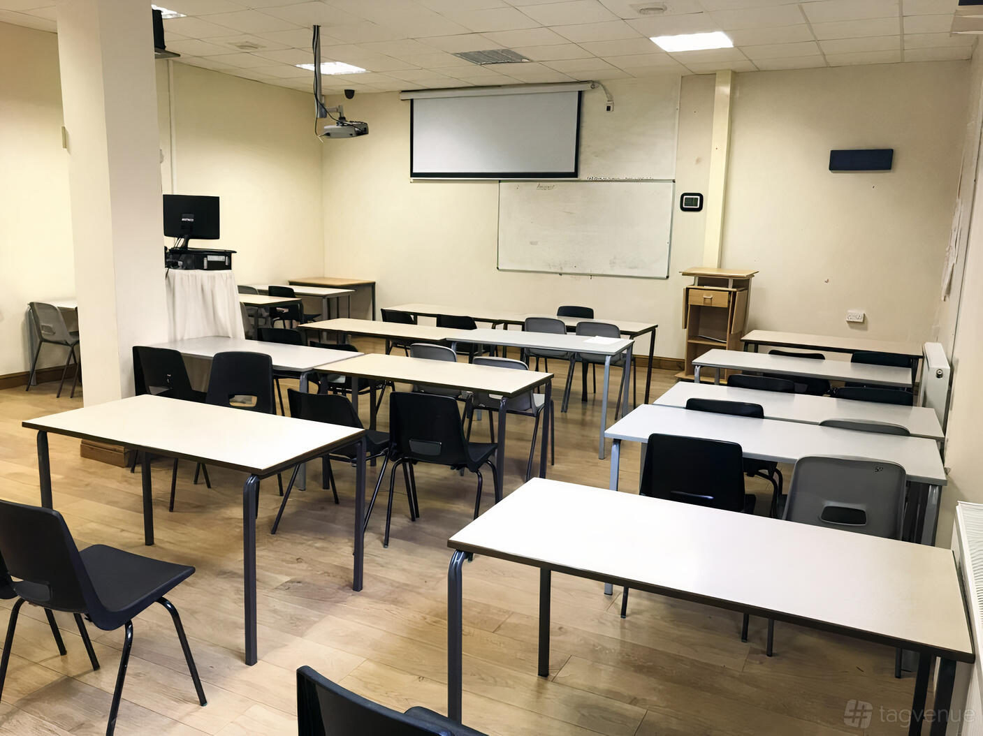 A function room with rows of rectangular tables, mixed chairs, a projector, and a whiteboard at ITC Centre.
