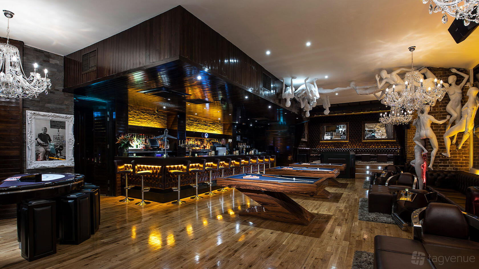 An upscale event lounge with billiards tables, a polished wooden bar, chandeliers, and leather seating at Q Shoreditch.