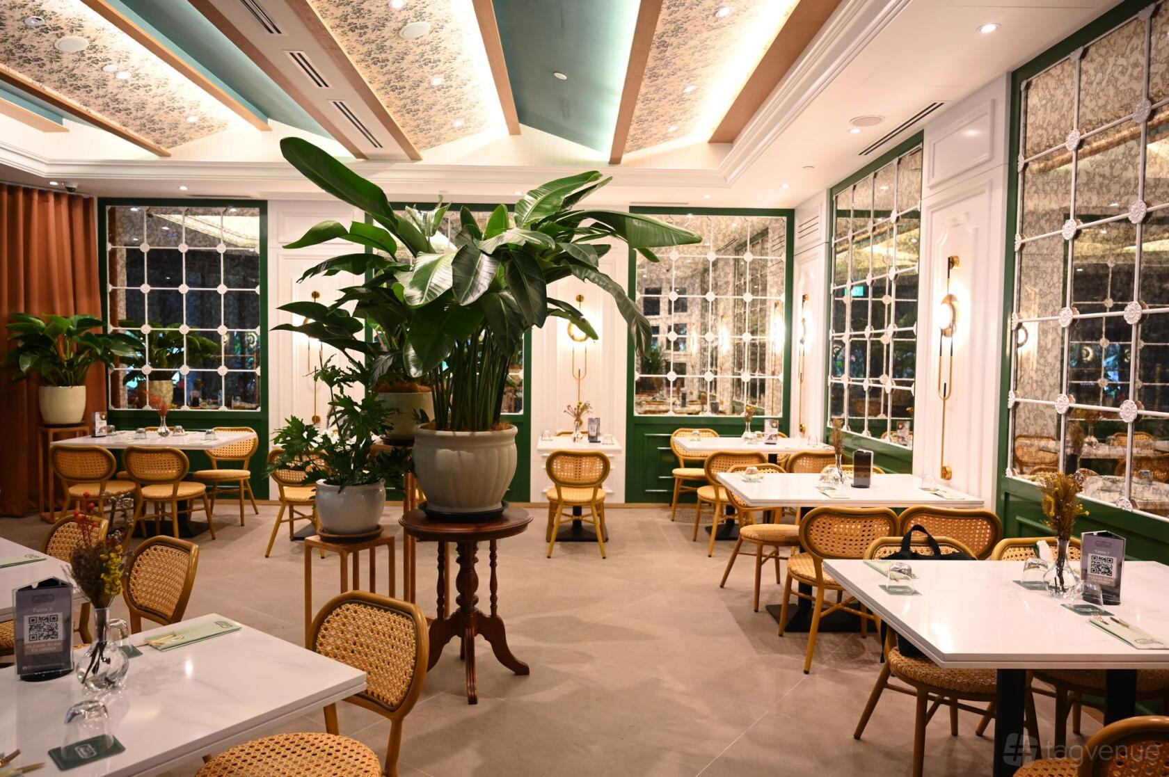A restaurant with rattan chairs, large potted plants, mirrored walls, and coffered ceilings at Tanglin Cookhouse (Paya Lebar Quarter).