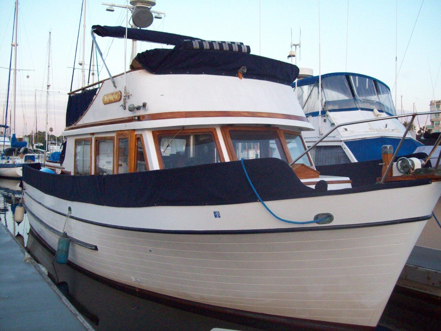 A docked boat with wood accents, upper deck, and protective canvas covers at The Blue Moon Dolphin Cruises.