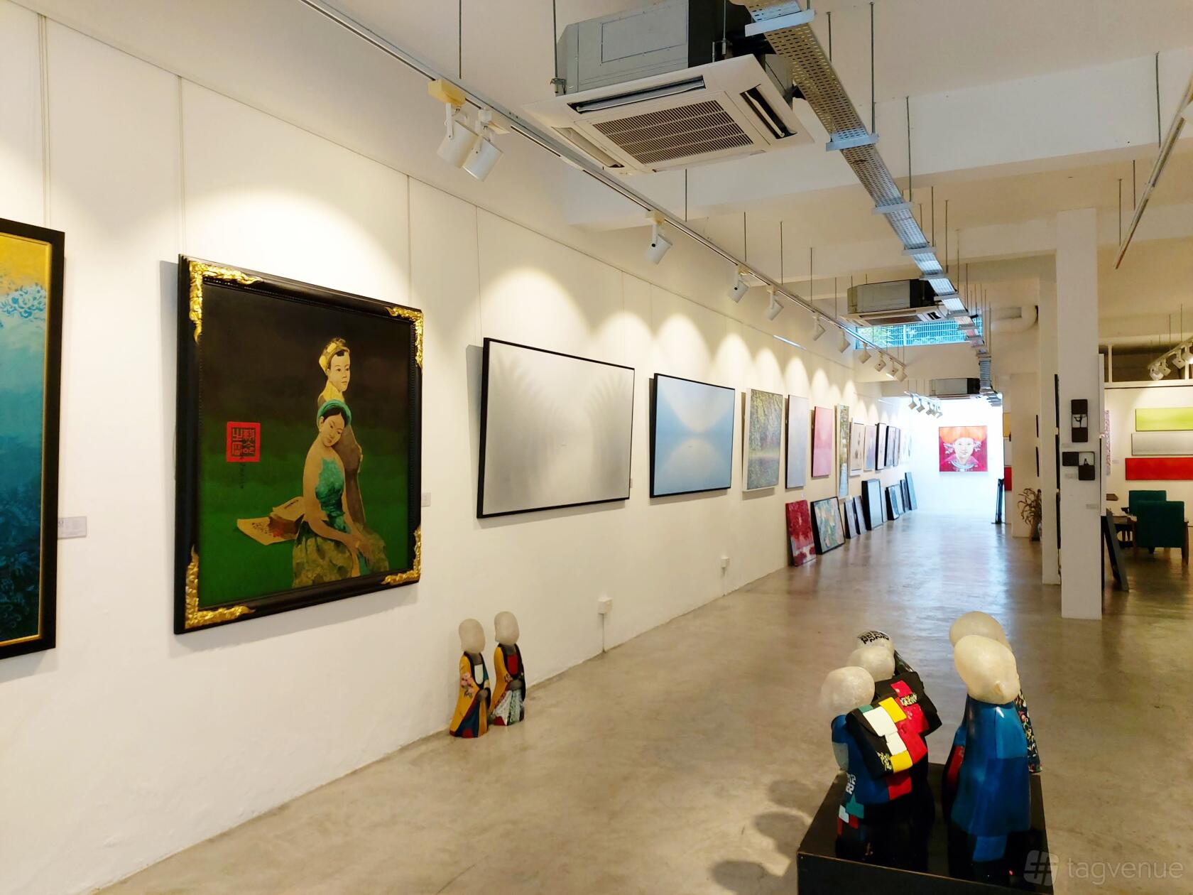 A gallery with white walls, concrete floors, ceiling spotlights, and colorful artworks at ArtBlue Studio.